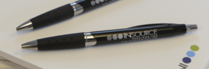 Insource Services branded pens laying on top of insource services note pads